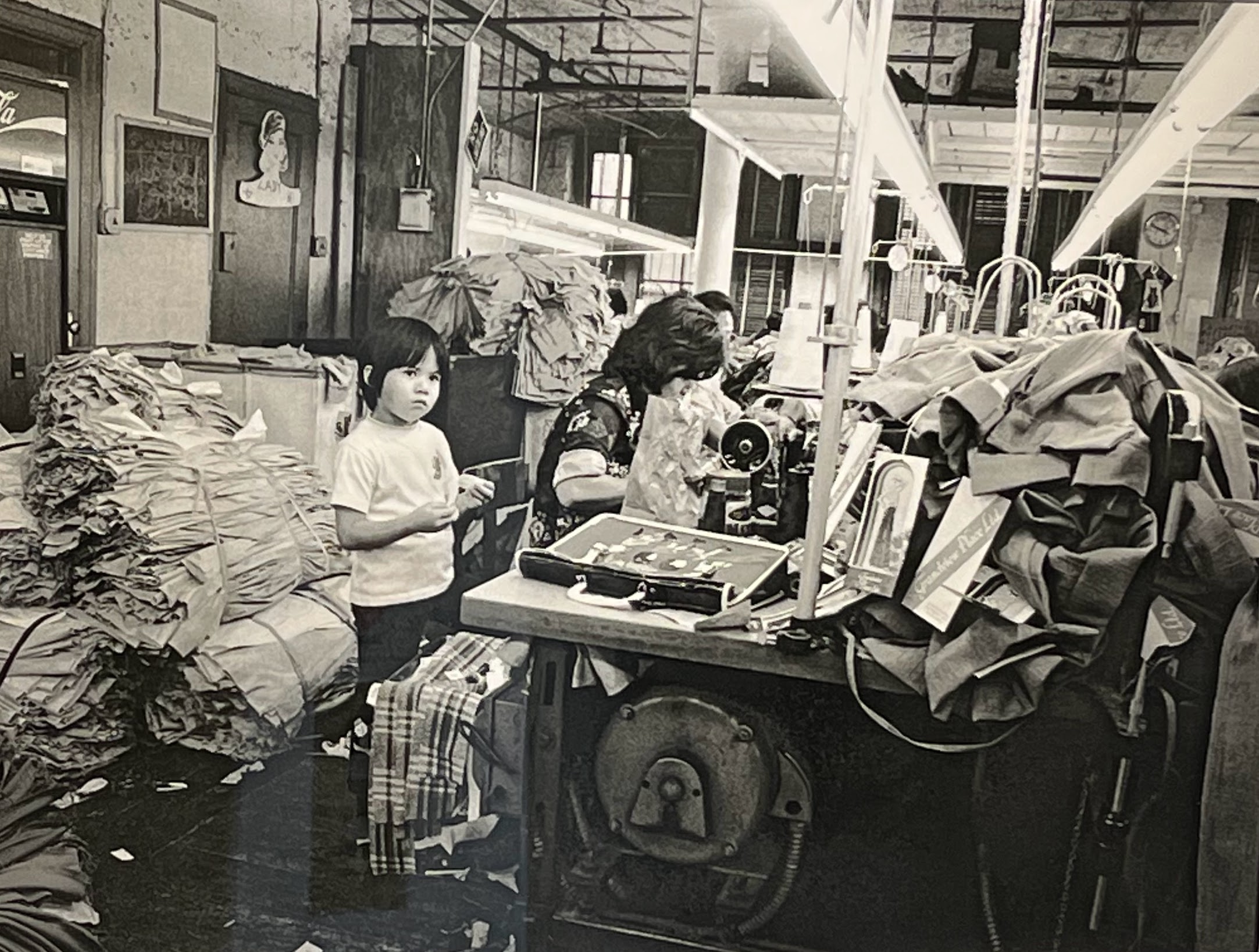 A child waits in a factory because their parent, a garment worker, has no other means of childcare, Chinatown, New York, 1976.